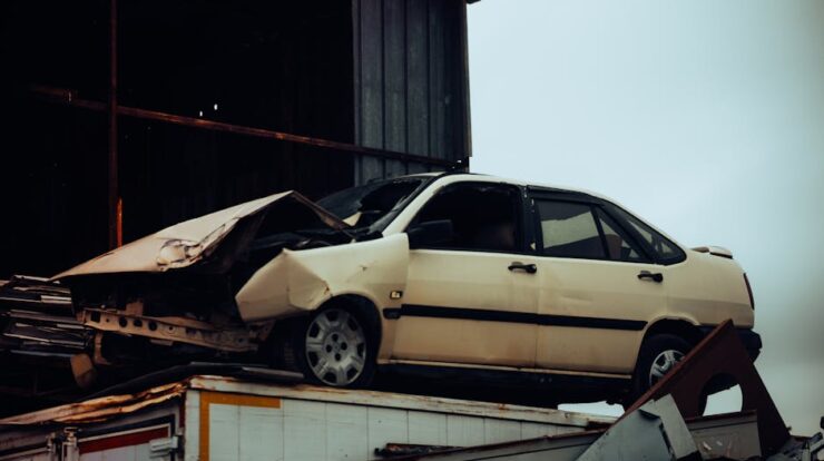 A damaged car sits atop a metal scrap heap, showing a scene of automotive decay. - Photo by UMUT ???????????? on Pexels